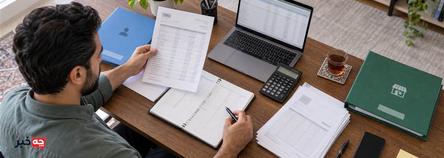 صاحب کسب‌وکار در حال تطبیق صورتحساب با دفتر و فاکتورها